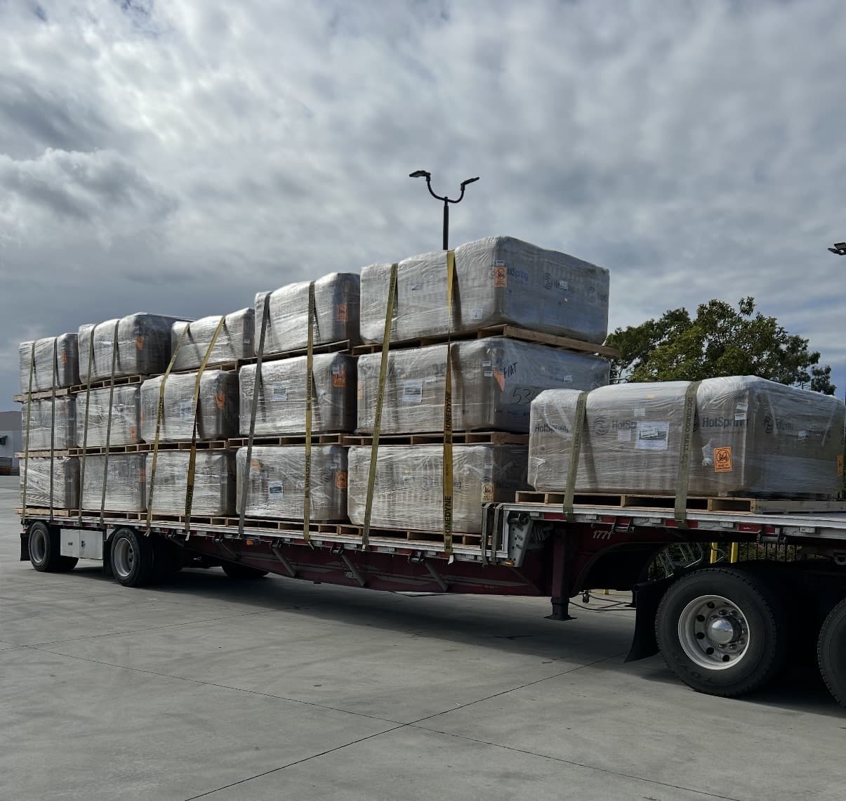 A commercial load of wrapped spas secured for transport.